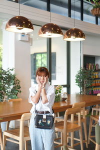 Worried young woman touching her cheeks while sitting in restaurant