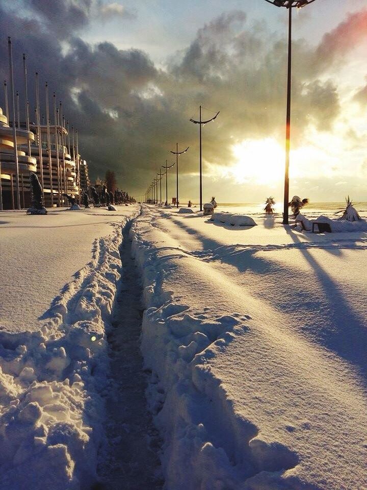 cold temperature, transportation, snow, winter, road, street, season, weather, car, sunlight, sunset, sun, mode of transport, cloud - sky, tranquil scene, sky, scenics, the way forward, nature, sunbeam, day, outdoors, tranquility, surface level, no people