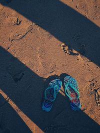 Directly above shot of flip-flops on sand at beach
