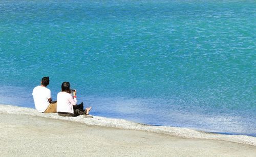 Rear view of people sitting on beach