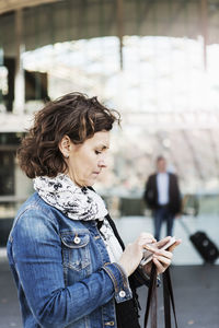 Side view of businesswoman using mobile phone outside railroad station