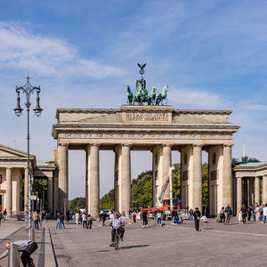 The brandenburg gate with street lamp and people as german landmark under blue sky, berlin, germany