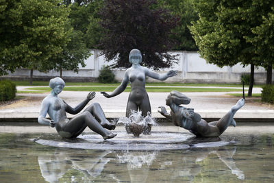 Statue of birds by lake against trees