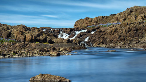 Rock formations by sea against sky