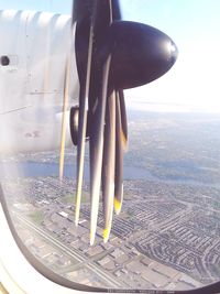 Close-up of airplane flying over landscape against sky