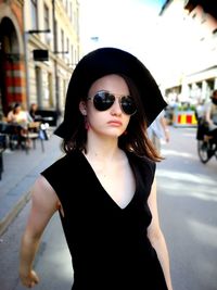 Portrait of woman wearing sunglasses standing on street in city