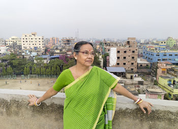 An aged bengali woman enjoying view of urban surroundings from rooftop of a building at howrah india