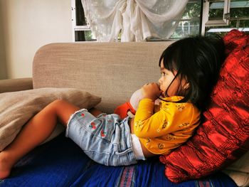 Midsection of child sitting on sofa at home