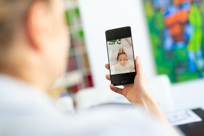 Rear view of woman talking on video call sitting at home