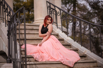 Portrait of woman sitting on railing