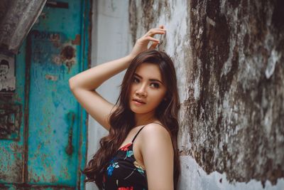 Portrait of young woman against wall