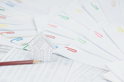 Close-up of model house with pencil on financial documents