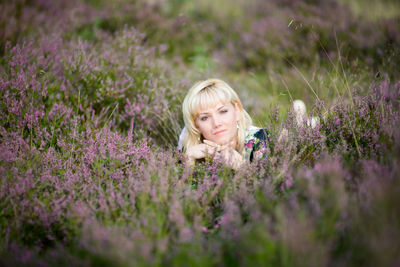 Young woman with purple flowers on field