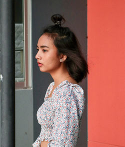 Portrait of young woman looking away against window