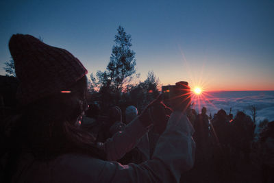 Silhouette people by tree against sky during sunset