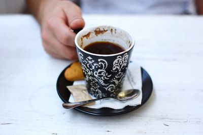 Cropped image of hand holding coffee cup on table