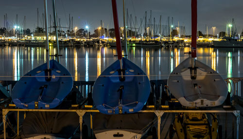 Sailboats moored in harbor against sky at night