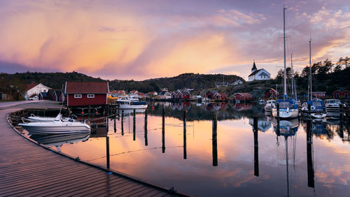 Boats moored at harbor against sky during sunset