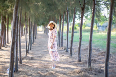 Full length of woman standing on field amidst trees