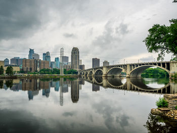 Bridge over river by buildings against sky