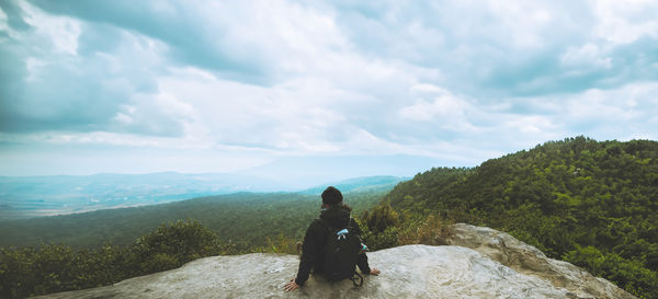 Rear view of man standing on mountain against sky