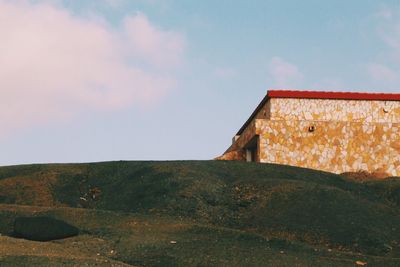 Low angle view of house on hill against sky