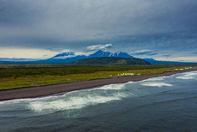 Scenic view of sea by mountains against sky