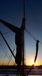 Low angle view of silhouette man standing on sailboat against sky during sunset