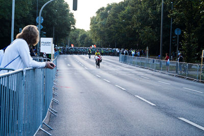 Side view of woman leaning on railing during sports event