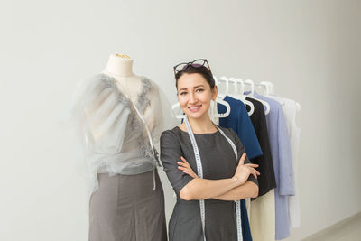 Smiling young woman standing against white wall