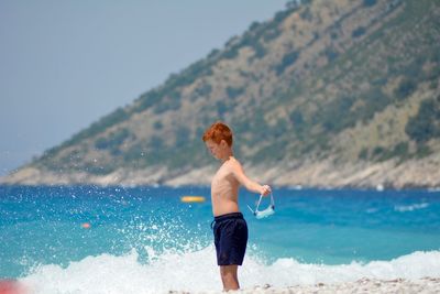 Shirtless boy standing on beach