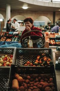 Senior woman buying fruits at market stall in city