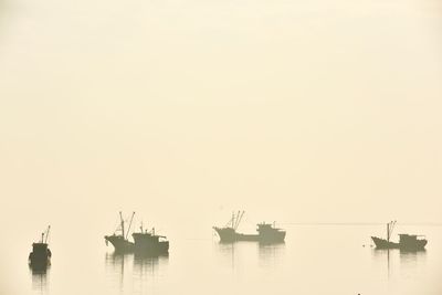 Silhouette boats in sea against clear sky