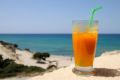 Drink on glass at beach against sky