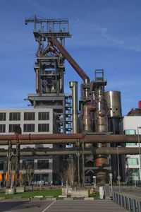 Low angle view of industry by building against sky