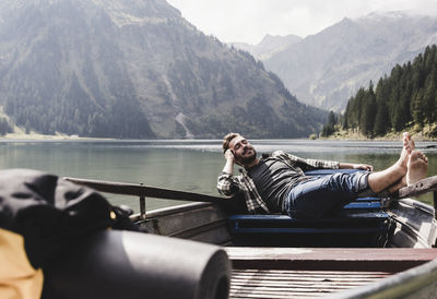 Austria, tyrol, alps, relaxed man in boat on mountain lake