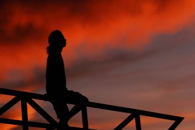 Silhouette woman standing against orange sky