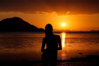 Silhouette woman looking at sea against sky during sunset