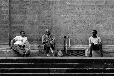 People sitting on bench against wall