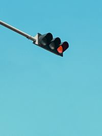 Low angle view of road sign against clear blue sky