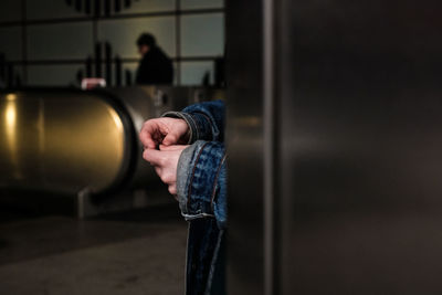 Midsection of person standing by metal