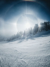 Scenic view of snow covered landscape against bright sun