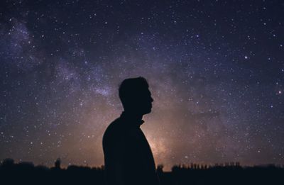 Silhouette man standing against star field at night