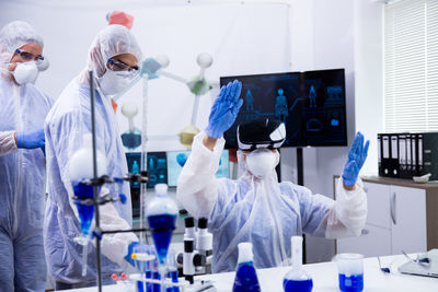 Scientist wearing virtual reality simulator colleague standing by side at laboratory