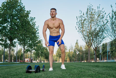 Portrait of shirtless man exercising in park