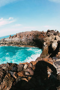 Scenic view of rocks by sea against sky