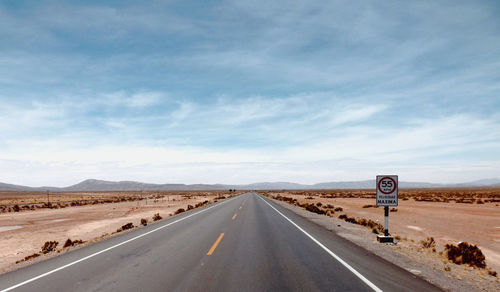 Road passing through desert against sky