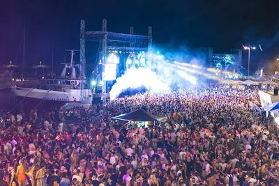Panoramic view of crowd at music concert at night