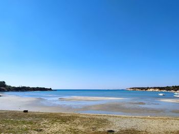 Scenic view of beach against clear blue sky