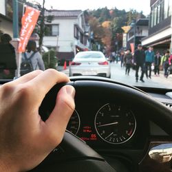 Cropped hand of man holding steering wheel of car